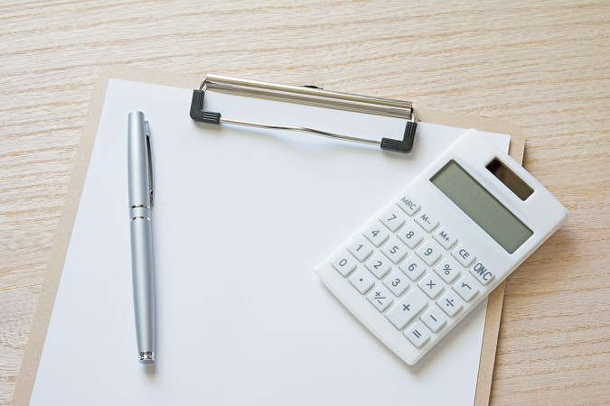 バインダーに挟まった紙と電卓とペン